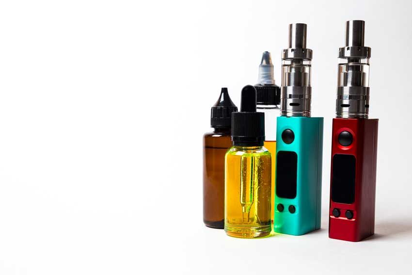 Colorful vaporizer devices and cannabis oil bottles on a white background. Colorful vaporizer devices and cannabis oil bottles on a white background.